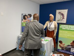 Staff member speaking to guest at Camden Healthy Start information table.