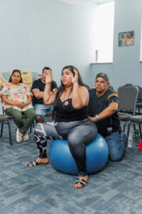 Pregnant mother being assisted by her partner while sitting on large medicine ball.